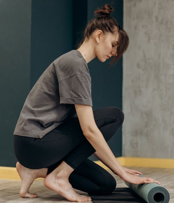 Woman in a peaceful yoga pose in a dimly lit room, suggesting calmness and sleep preparation.